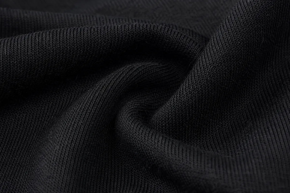 A close-up of black ribbed knit fabric with soft folds and a smooth texture.