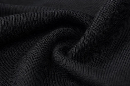 A close-up of black ribbed knit fabric with soft folds and a smooth texture.