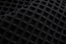 Close-up of a black waffle-knit fabric texture with a diamond grid pattern.