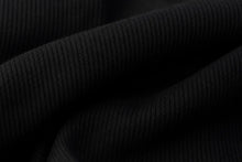 Close-up of black ribbed fabric with soft folds and a fine knit texture.