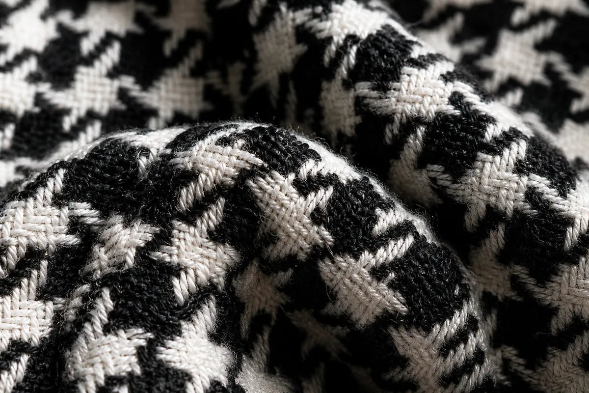 A close-up of a black and white houndstooth knit fabric with a textured woven pattern.