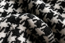 A close-up of a black and white houndstooth knit fabric with a textured woven pattern.
