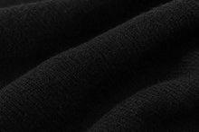 A close-up of black textured fabric with soft folds and a fine woven surface.