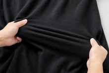 A close-up of a person's hands stretching and demonstrating the elasticity of a solid black fabric.