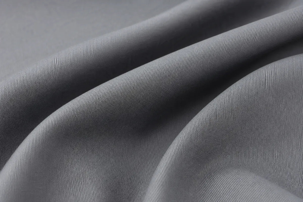 A close-up of draped gray fabric with a fine ribbed texture, showing soft folds and shadows.