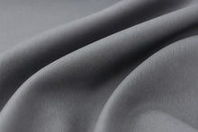 A close-up of draped gray fabric with a fine ribbed texture, showing soft folds and shadows.
