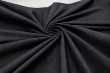 A close-up of dark charcoal gray fabric arranged in a spiral drape, showing the material texture and folds against a light neutral background.