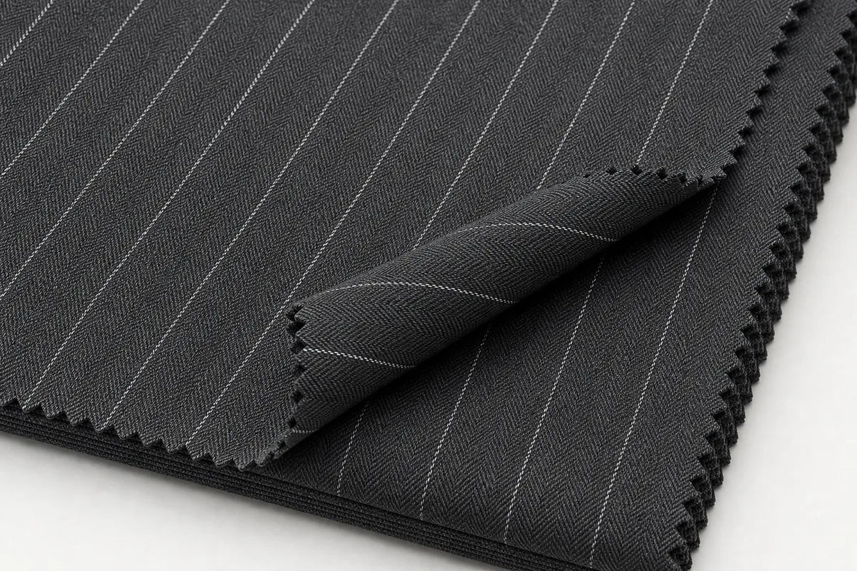 Dark gray pinstriped fabric with fine white vertical lines, folded over to show the zigzag cut edges on a white background.
