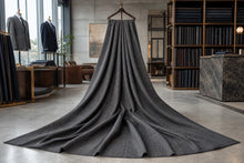 A dark gray textured knit blanket or throw draped from a hanger in a modern, stylishly decorated clothing showroom.
