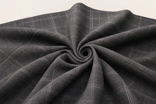 Dark gray plaid fabric draped in a spiral pattern, showing its woven texture and subtle grid lines on a light background.