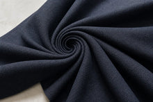 Dark navy blue textured fabric draped in a spiral pattern, showing a fine woven herringbone texture.
