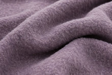 A close-up of draped, textured fleece fabric in a muted dusty lavender-purple color.