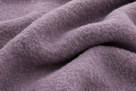 A close-up of draped, textured fleece fabric in a muted dusty lavender-purple color.