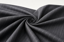 Dark gray pinstriped fabric draped in a spiral pattern against a light gray background.