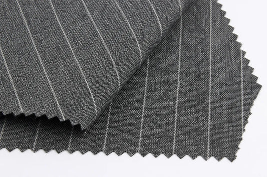 Dark gray pinstriped fabric with fine white vertical stripes, folded to show texture and scalloped cut edges on a white background.