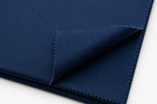 A close-up of folded navy blue fabric with a visible woven texture and zigzag-cut edges, photographed on a white background.