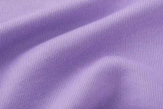 A close-up of lavender purple ribbed knit fabric with soft folds and a smooth texture.