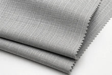 A close-up of folded light gray fabric with a subtle woven texture and zigzag-cut edges, shown on a plain white background.