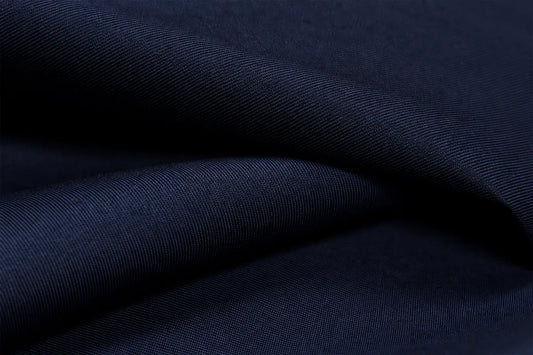 A close-up of dark navy blue fabric with a fine ribbed texture, shown in soft folds.