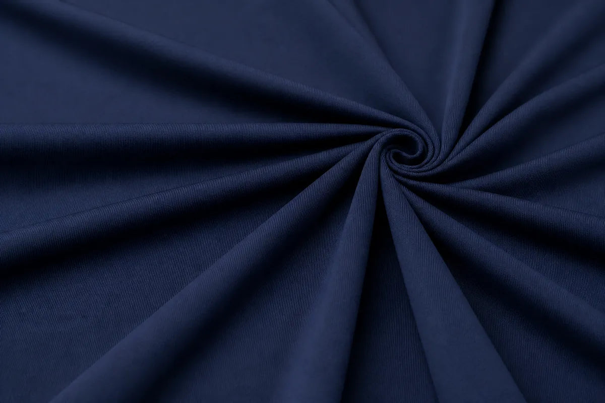 A close-up of dark navy blue fabric arranged in a spiral drape pattern, showing the material texture and color.