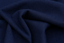 A close-up of draped navy blue fabric with visible woven texture and soft folds.