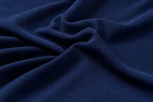 A close-up of draped navy blue fabric with soft folds and a smooth woven texture.