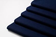 A close-up of folded navy blue woven fabric stacked diagonally on a plain white background.