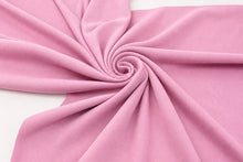 A close-up of draped pink fabric arranged in a spiral pattern on a white background.