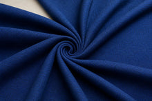 A close-up of deep blue textured fabric arranged in a spiral drape, showing the material's weave and color.