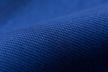 A close-up of dark blue textured fabric with a fine woven pattern, showing soft folds and shadows.