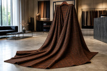 A large brown plaid wool blanket draped over a hanger in a modern, stylishly decorated clothing store.