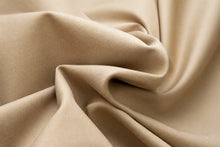 A close-up of draped beige fabric with soft folds and a smooth texture.