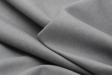 A close-up of draped gray fabric with a fine ribbed texture, showing soft folds and shadows.