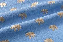 Blue fabric with a repeating pattern of gold elephants, shown in soft folds.