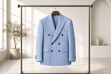 A light blue double-breasted pinstripe blazer with black buttons, hanging on a wooden hanger from a black clothing rack in a bright, modern minimalist room.