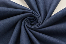 A close-up of dark blue textured fabric arranged in a spiral swirl, showing the material's weave and drape against a light neutral background.