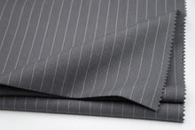 Dark gray pinstriped fabric folded over on a white background, showing fine vertical white stripes and serrated edges.