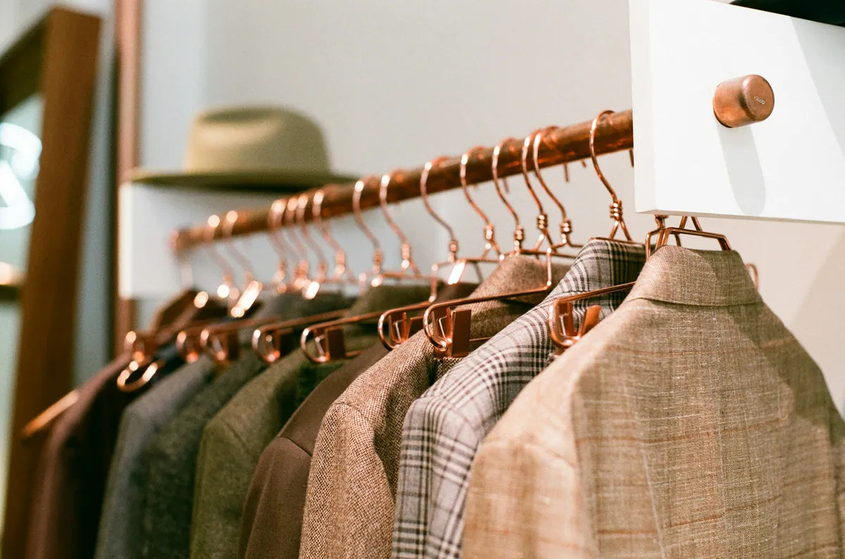 Hangers with jackets and a hat on a rack in a store setting