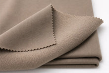 A folded piece of taupe knit fabric with serrated edges, shown on a plain white background.
