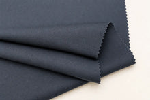 A folded piece of dark navy blue fabric with zigzag-cut edges, displayed on a clean off-white background.
