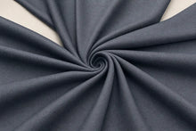 A close-up of dark slate gray fabric arranged in a spiral drape pattern, showing its texture and color.