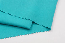 A close-up of folded turquoise fabric with zigzag-cut edges on a plain white background.