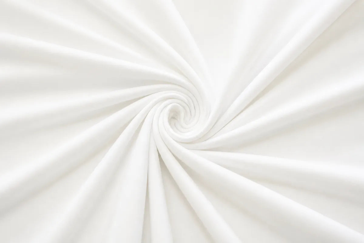 White fabric draped in a spiral swirl pattern, showing soft folds and a smooth texture.